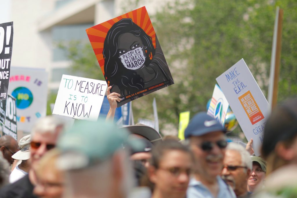 Photo: protesters march at the People's Climate March while holding signs bearing slogans in support of scientists