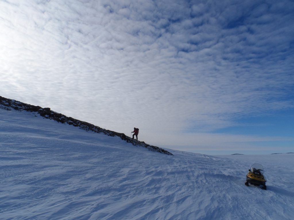 Photo: a scientist leaves his snowmobile to climb a rocky slope